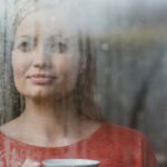 woman looking out window with coffee