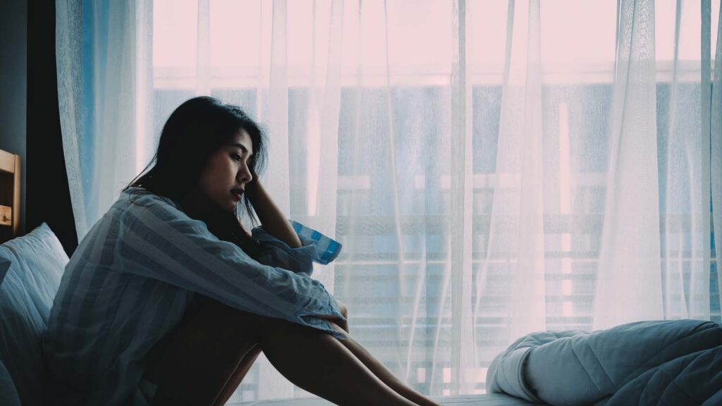 Woman sitting in bed while saddened