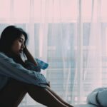 Woman sitting in bed while saddened