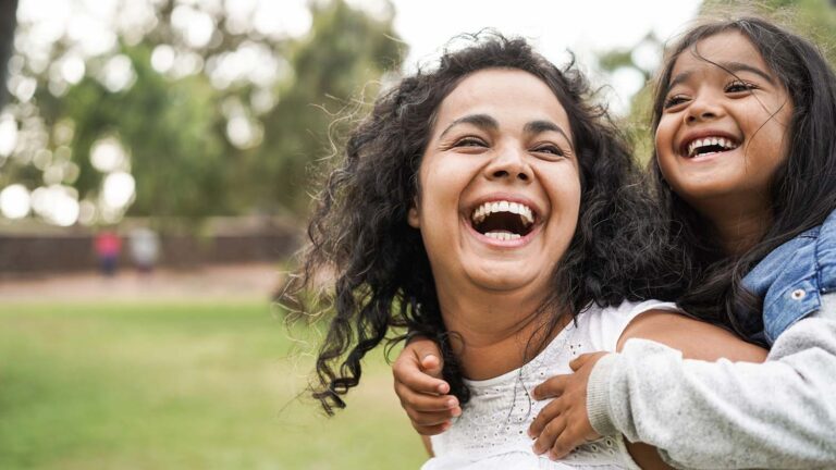 woman laughing with child on back
