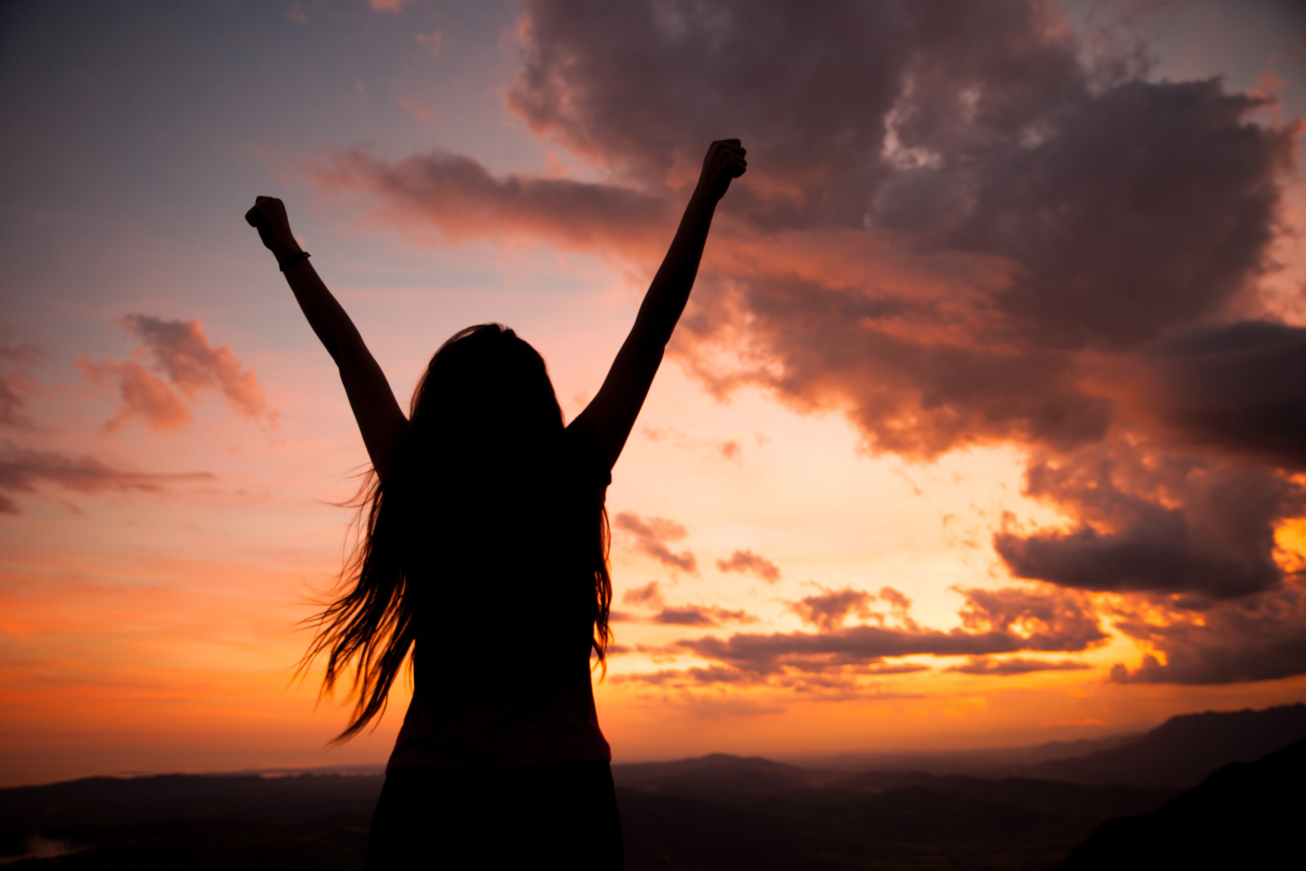 woman gesturing success - silhouette over evening sky