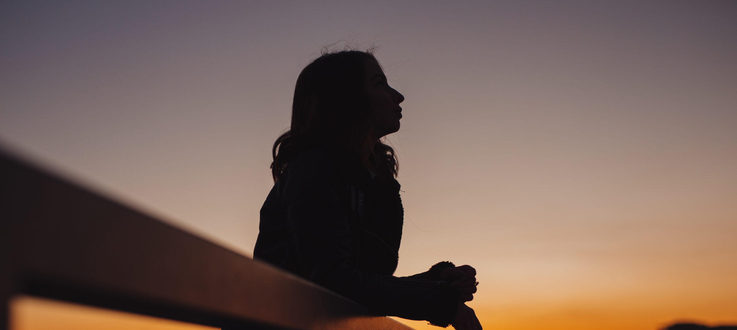 Silhouette of woman thinks and dreams about future at sunset in city