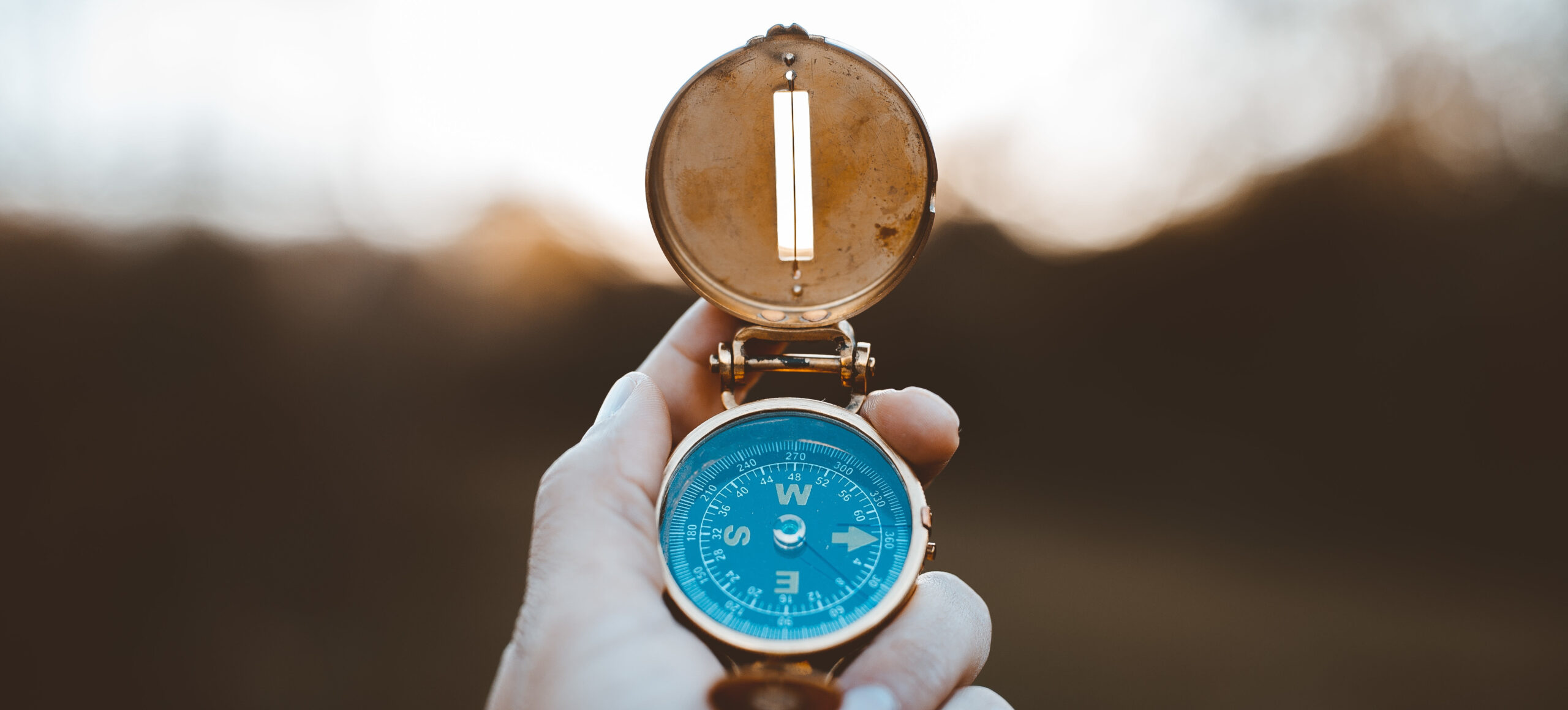 A closeup shot of a person holding a compass with a burred background