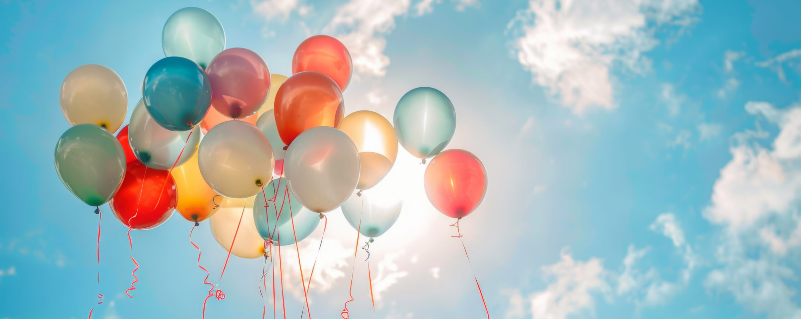 A bunch of vibrant balloons floating gracefully in the air against a clear blue sky.