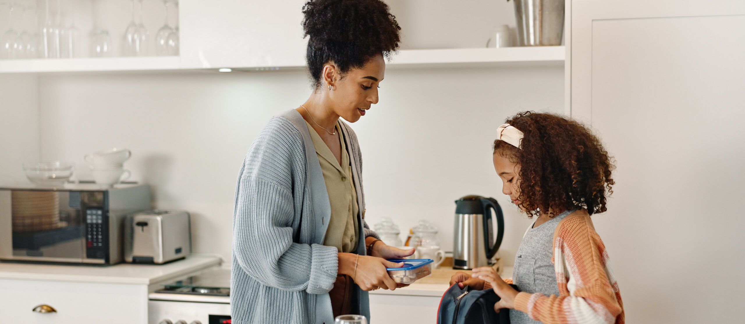 Mother, child and lunchbox with backpack packing in home kitchen or nutrition, meal or morning. Woman, daughter and young student for learning development or school food for wellness, health or snack.